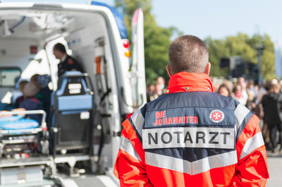 Ein Notarzt steht vor einem Rettungswagen.