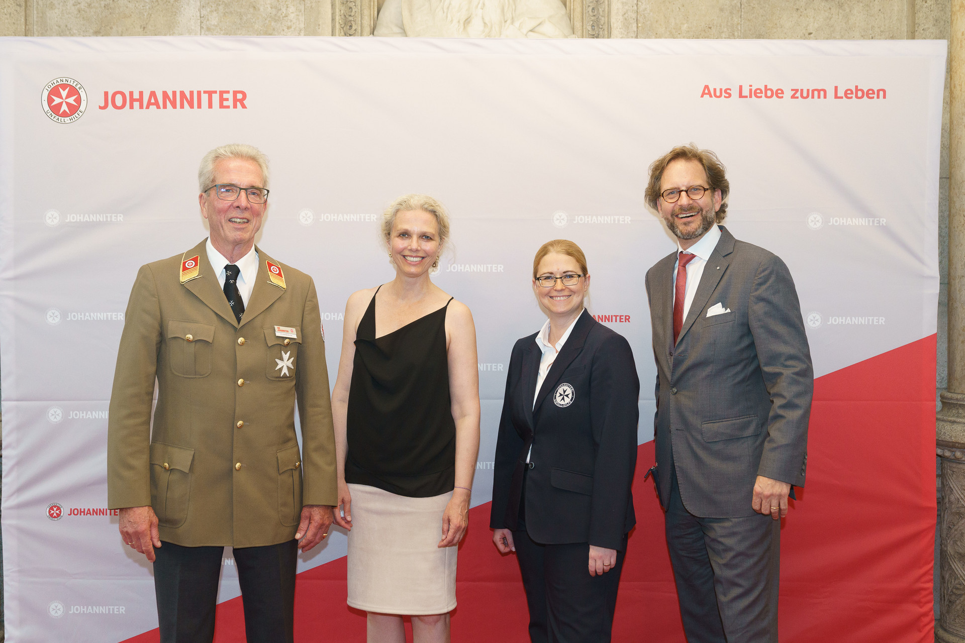 Präsident Johannes Bucher und Bundesgeschäftsführerin Petra Grell-Kunzinger mit Personen vor einer Johanniter Leinwand