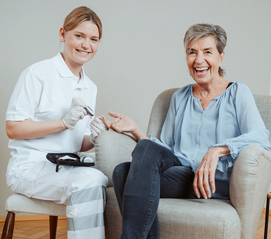 Eine Pflegerin misst den Blutzucker ihrer Patientin.