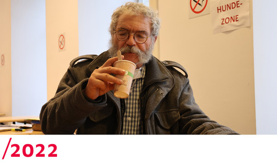 2022: Ein älterer Mann trinkt aus einem Becher in der Wärmestube.