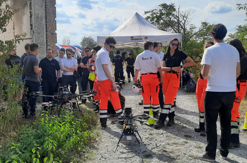 Eine Gruppe Johanniter bei einem Übungseinsatz. Zwischen den Personen stehen zwei große Drohnen am Boden.