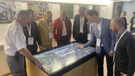 Mitarbeiter des Forschungsprojekts schauen sich eine Lagedarstellung auf einem großen Monitor an. 