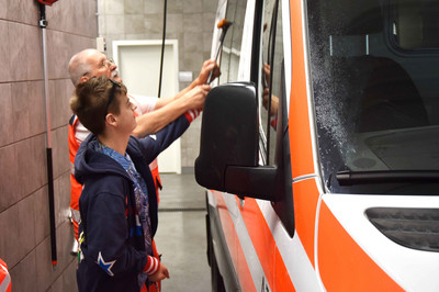Gemeinsam mit einem Johanniter wird das Rettungsauto gewaschen.