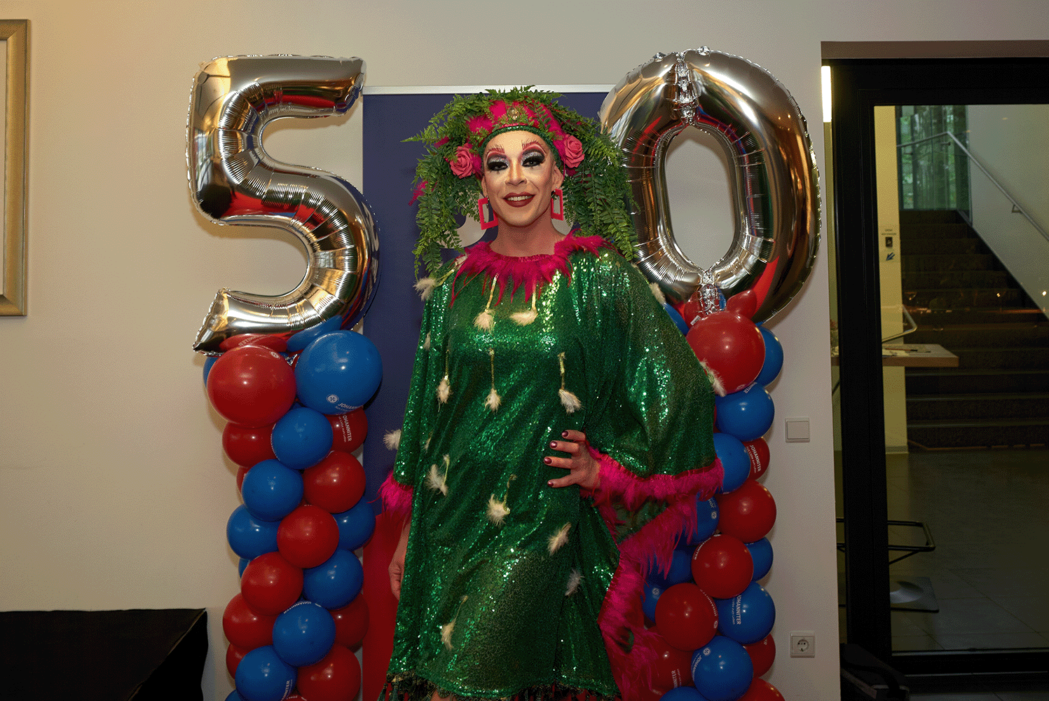 Dragqueen steht vor einem 50er Ballon und posiert vor der Kamera