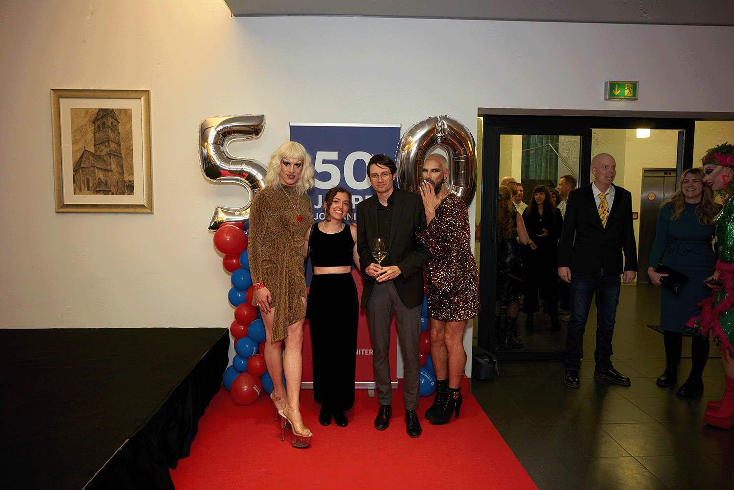 Personen stehen vor einem 50er Ballon und posieren vor der Kamera