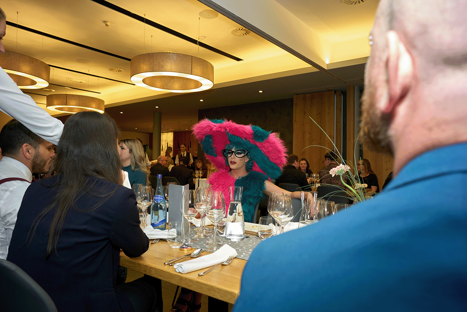 Personen sitzen mit Dragqueen an einem Tisch