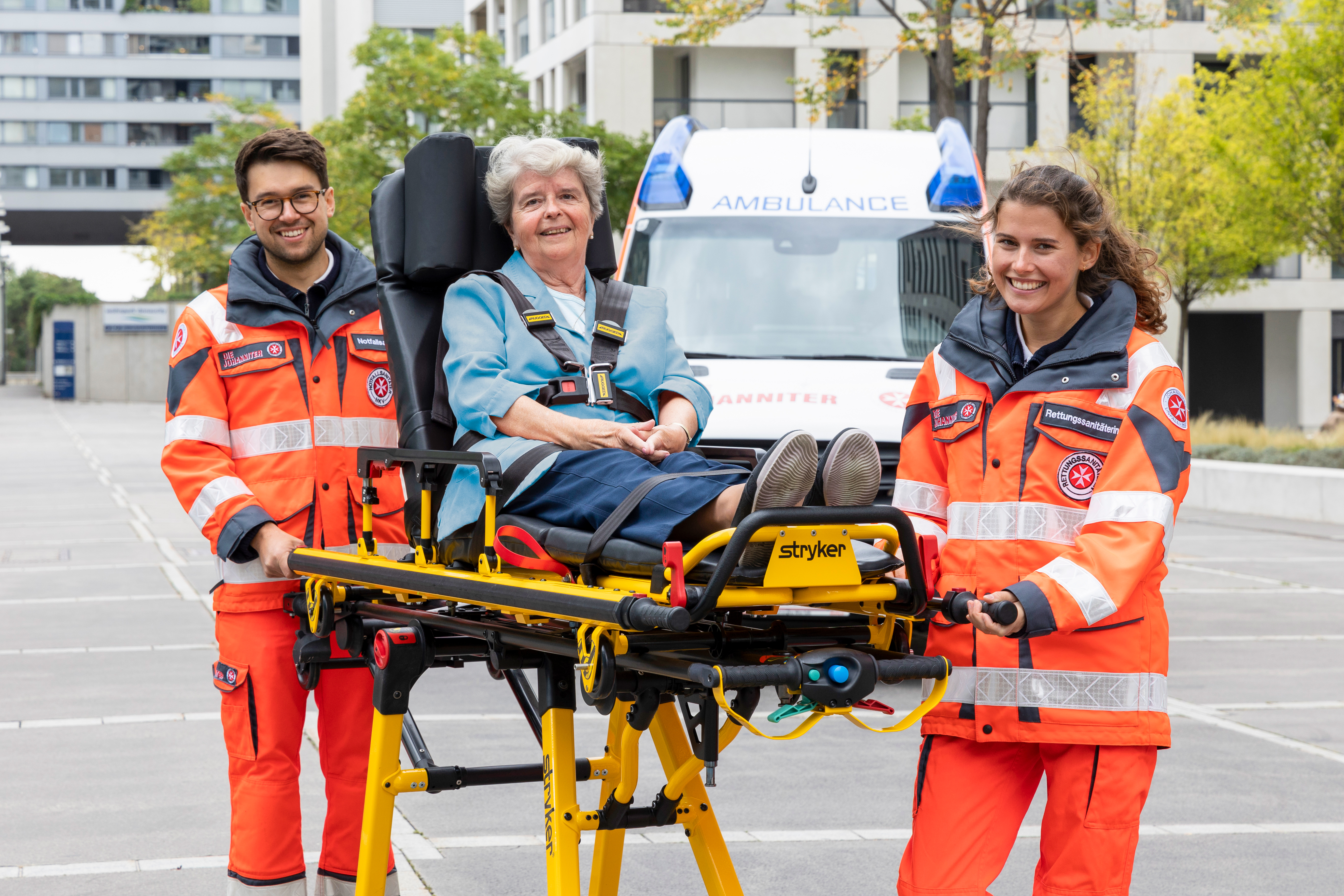 Zwei ehrenamtliche Sanitäter:innen transportieren eine Patientin auf einer Fahrtrage.