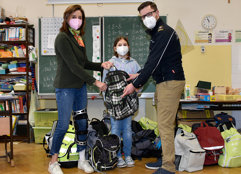 Eine Lehrerin und eine Schülerin mit einem Johanniter bei der Spendenübergabe der Volksschule Sievering