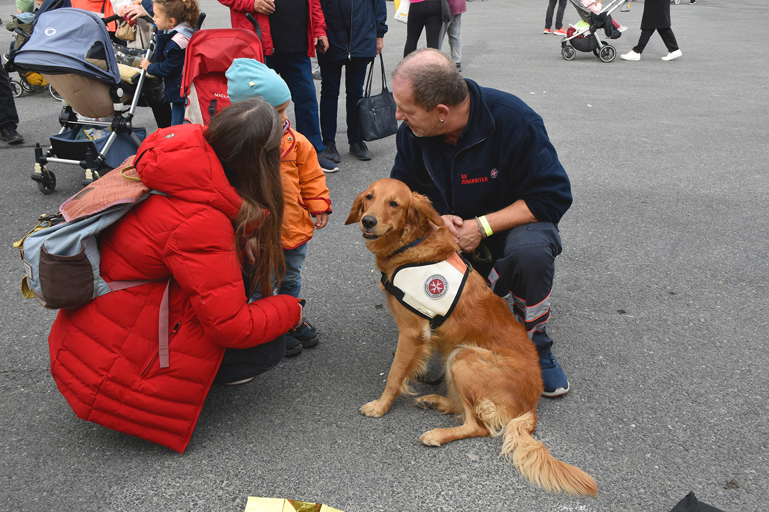 Ein kleiner Junge steht mit seiner Mutter neben einem Rettungshund.